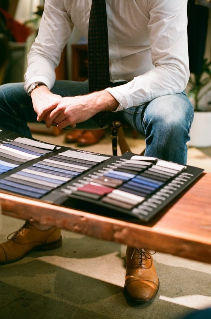 a man sitting at a table with a display of ties on it